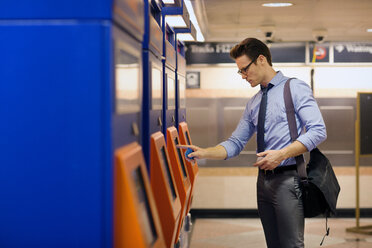 Geschäftsmann kauft Fahrkarte am Automaten in der U-Bahn-Station - CAVF22509