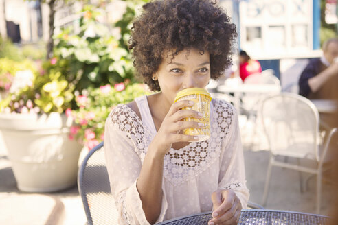Frau trinkt Kaffee, während sie in einem Straßencafé sitzt - CAVF22546
