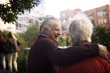 Happy senior man with arm around woman in city - CAVF22563