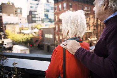 Älteres Paar mit Blick auf die Stadt, während es auf dem Balkon steht - CAVF22565