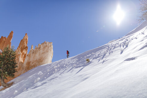 Low angle view of hiker walking on snow covered mountain against sky during sunny day - CAVF22571