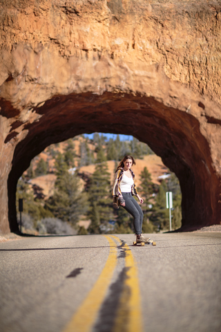 Hiker skateboarding on road against rocky tunnel at Bryce Canyon National Park stock photo