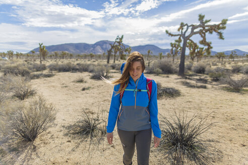 Female hiker with backpack walking on field at Joshua Tree National Park - CAVF22584