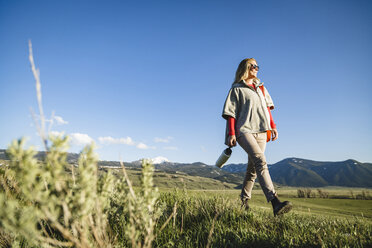 Low angle view of female hiker walking on field against sky - CAVF22604