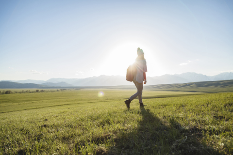 Wanderin in voller Länge auf grasbewachsenem Feld gegen den Himmel, lizenzfreies Stockfoto
