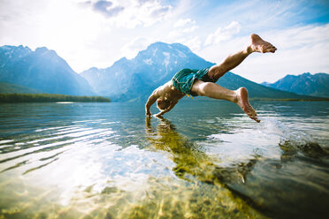 Man diving into lake against mountains and sky - CAVF22616