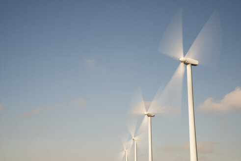 Niedriger Blickwinkel auf Windkraftanlagen in Bewegung gegen den Himmel - CAVF22636