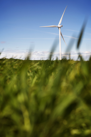 Windkraftanlage auf einer Wiese gegen den Himmel, lizenzfreies Stockfoto