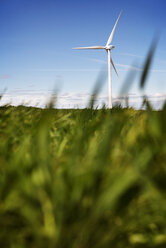 Wind turbine on grassy field against sky - CAVF22659