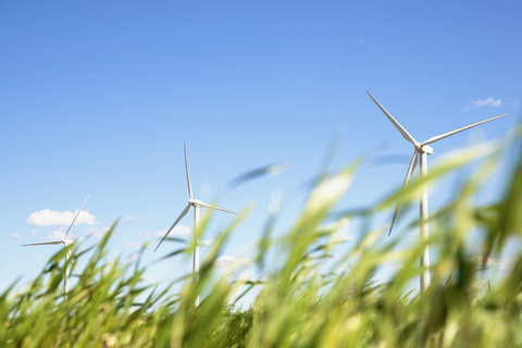 Wind turbines on grassy field against blue sky stock photo