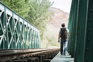 Rear view of man walking on railway bridge - CAVF22686