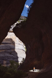 Distant view of male hiker standing in cave - CAVF22695