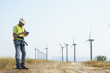 Ingenieur mit Tablet-Computer im Windpark gegen den Himmel - CAVF22701