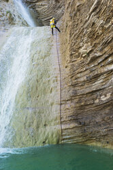 Niedriger Blickwinkel von Frau kletternden Berg durch Wasserfall - CAVF22706