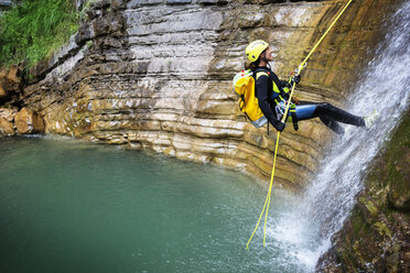 Side view of woman rappelling down into lake - CAVF22713