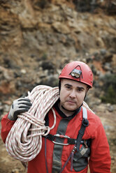 Porträt eines Bergsteigers, der ein Seil trägt, während er am Felsen steht - CAVF22740
