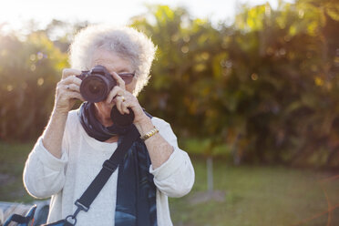Ältere Frau fotografiert durch die Kamera im Park - CAVF22759