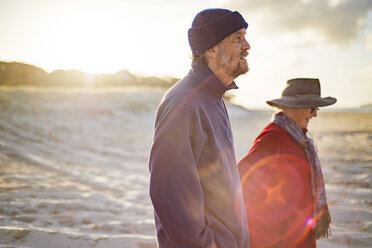 Glückliches älteres Paar beim Spaziergang am Strand an einem sonnigen Tag - CAVF22771