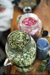 High angle view of dry herbs and petals in glass containers on table - CAVF22790