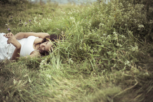 Frau liegend auf grasbewachsenem Feld - CAVF22851