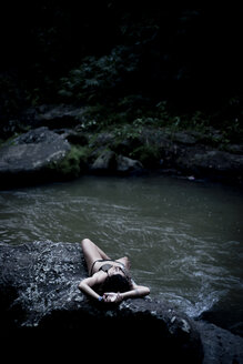 Frau liegt auf einem Felsen am Fluss - CAVF22880