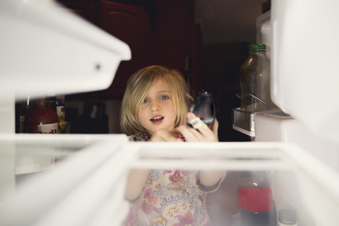 Nettes Mädchen schaut in den Kühlschrank zu Hause, lizenzfreies Stockfoto