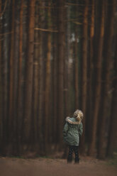 Rückansicht eines Mädchens, das gegen Bäume im Wald steht - CAVF22942