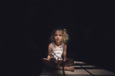 Porträt eines nachdenklichen Mädchens, das in der Dunkelkammer auf dem Boden sitzt, an einem sonnigen Tag - CAVF22965