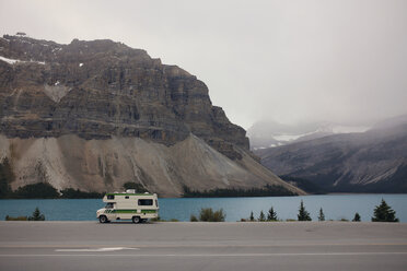 Motor home moving on road by river and mountains during foggy weather - CAVF23023