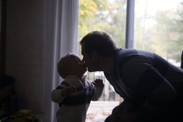 Vater und Sohn küssen sich, während sie zu Hause am Fenster stehen - CAVF23036