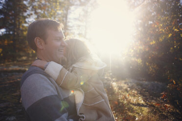 Happy father carrying daughter while standing at park during sunny day - CAVF23037