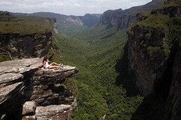 Blick auf eine Frau in mittlerer Entfernung, die auf einer Klippe im Nationalpark Chapada Diamantina sitzt - CAVF23051