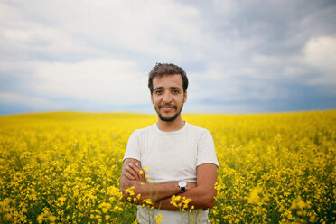 Portrait of confident man standing arms crossed in rapeseed field against sky - CAVF23058