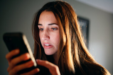 Close-up of woman using smart phone at home - CAVF23059
