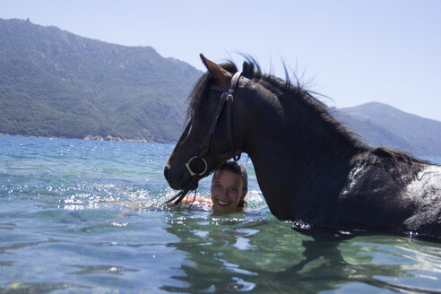 Portrait of happy woman with horse in river against mountains - CAVF23080