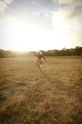 Happy girl playing on grassy field against sky - CAVF23096