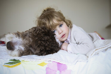 Portrait of girl relaxing with dog on bed at home - CAVF23118