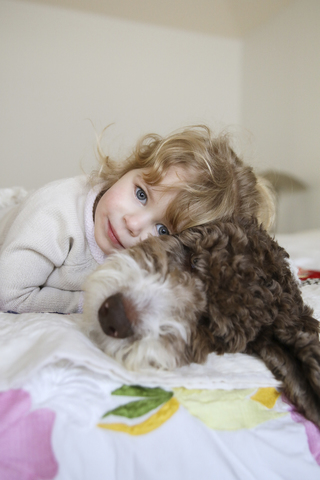 Portrait of happy girl relaxing with dog on bed at home stock photo