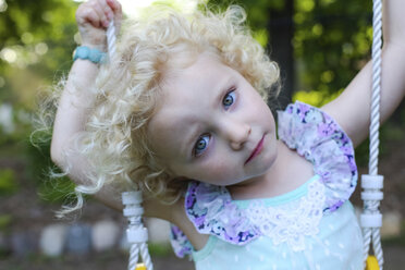 Porträt eines Mädchens, das auf einer Schaukel auf einem Spielplatz sitzt - CAVF23126