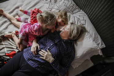 Draufsicht auf glückliche Enkeltöchter mit Großmutter auf dem Bett - CAVF23139