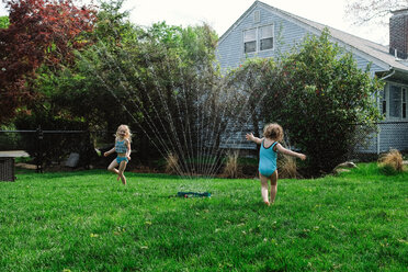 Mädchen spielen mit Sprühwasser auf dem Rasen - CAVF23155