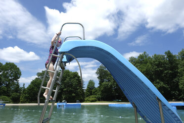 Seitenansicht des Mädchens klettern Schritte der Wasserrutsche in Resort gegen bewölkten Himmel - CAVF23182