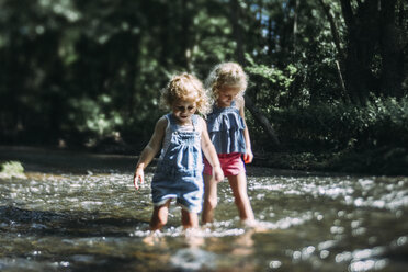 Sisters wading in lake during sunny day - CAVF23188