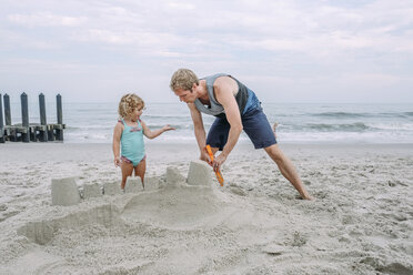 Father making sand castle by daughter at Cape May Beach against sky - CAVF23203
