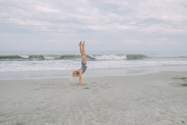 Handstand eines Mädchens in voller Länge am Cape May Beach gegen Meer und Himmel - CAVF23204