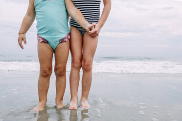 Low section of sisters standing at Cape May Beach against sky and sea - CAVF23206