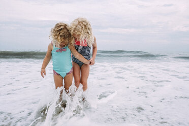 Schwestern spielen in den Wellen am Cape May Beach gegen Himmel und Meer - CAVF23207