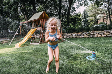 Happy girl playing in sprinkler at park - CAVF23227