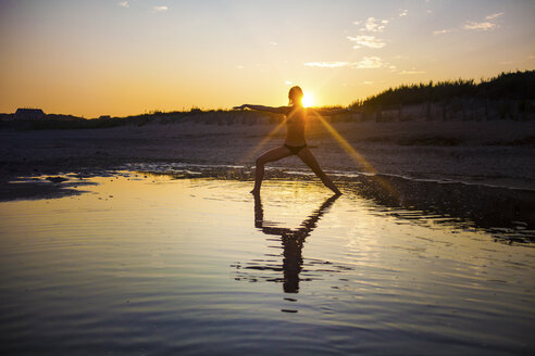 Frau im Bikini macht Yoga am Strand bei Sonnenuntergang - CAVF23279