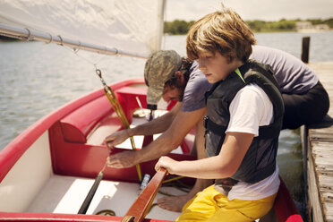 Vater und Sohn bereiten sich auf eine Bootsfahrt im See gegen den Himmel vor - CAVF23286